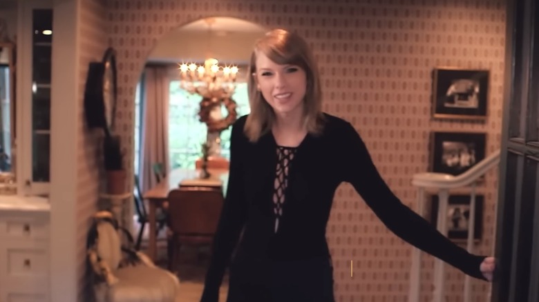Taylor Swift souriant et ouvrant la porte