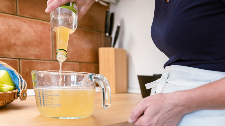 Femme versant du vinaigre dans un bol à mesurer