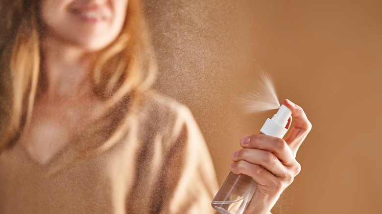 Femme pulvérisant un liquide à partir d'un vaporisateur