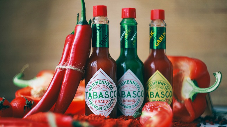 Bouteilles de Tabasco à côté de poivrons rouges