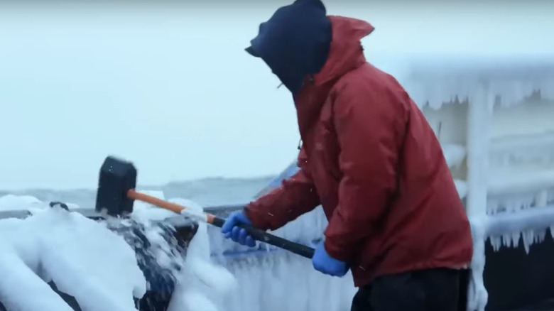  Un homme brise la glace sur un bateau