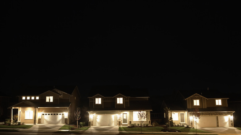 Trois maisons avec des lumières extérieures allumées