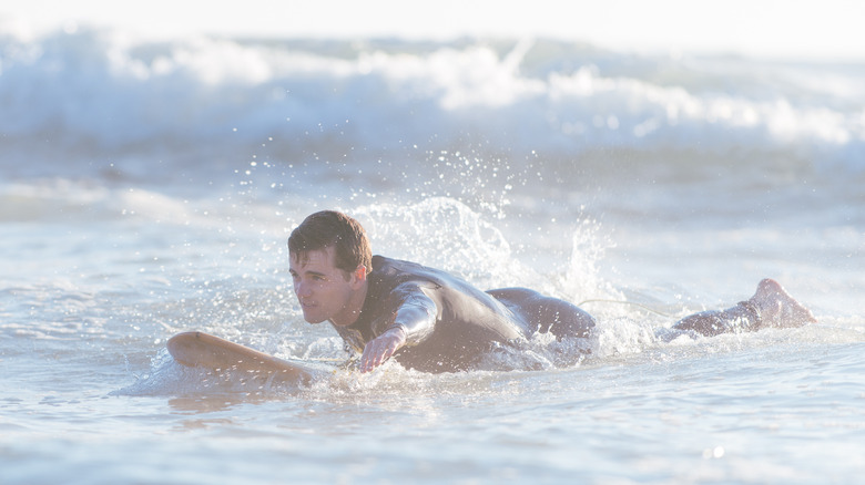 Surfeur pagayant vers le rivage