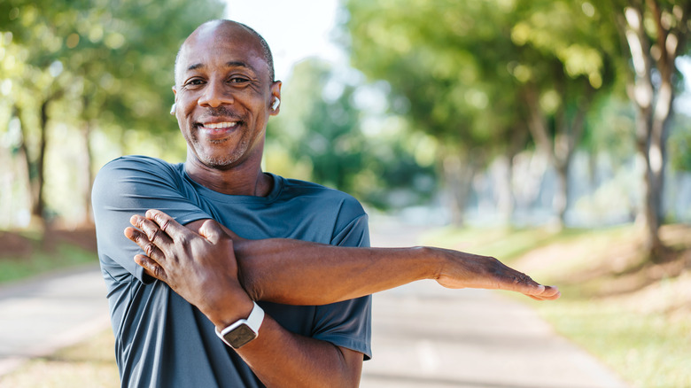 Homme souriant étirant le bras à l'extérieur