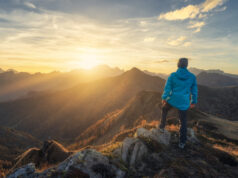 Homme debout sur une colline surplombant les montagnes