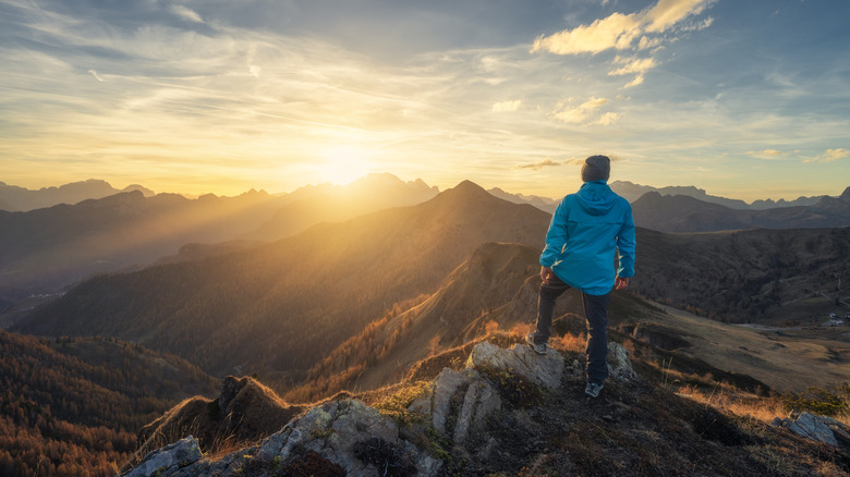 Homme debout sur une colline surplombant les montagnes