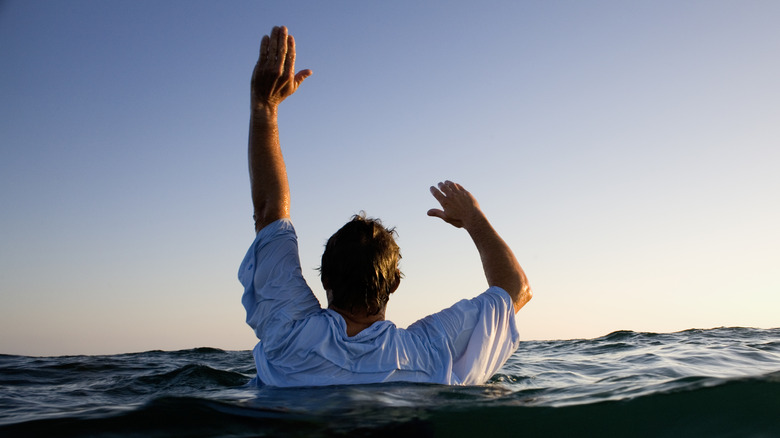 homme dans l'eau avec les mains levées