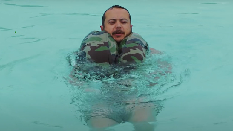 Homme flottant sur l'eau avec un pantalon comme dispositif de flottaison