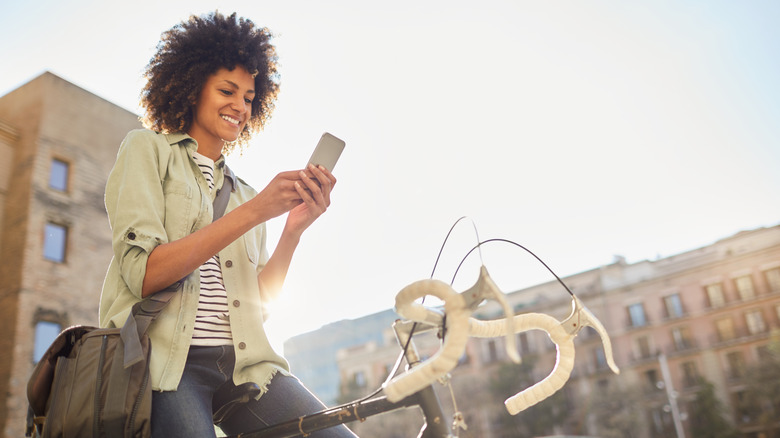 Femme assise sur un vélo, regardant le téléphone