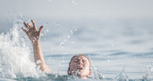 personne paniquée dans l'eau avec la main levée