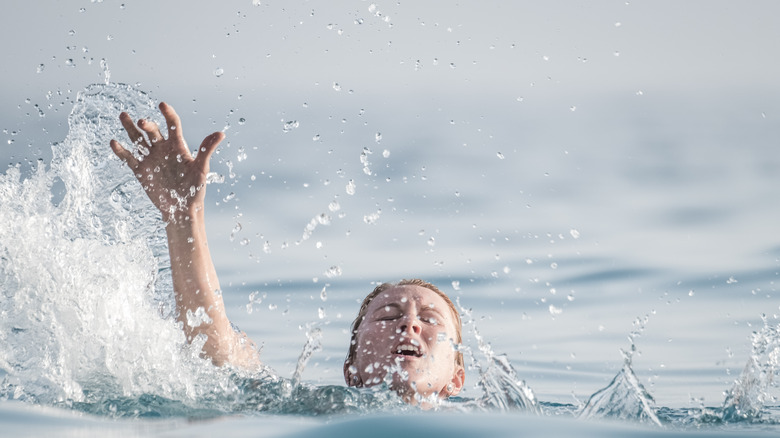 personne paniquée dans l'eau avec la main levée