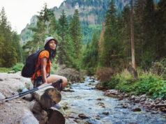 femme assise près d'un ruisseau en randonnée