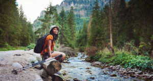 femme assise près d'un ruisseau en randonnée