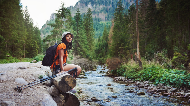 femme assise près d'un ruisseau en randonnée